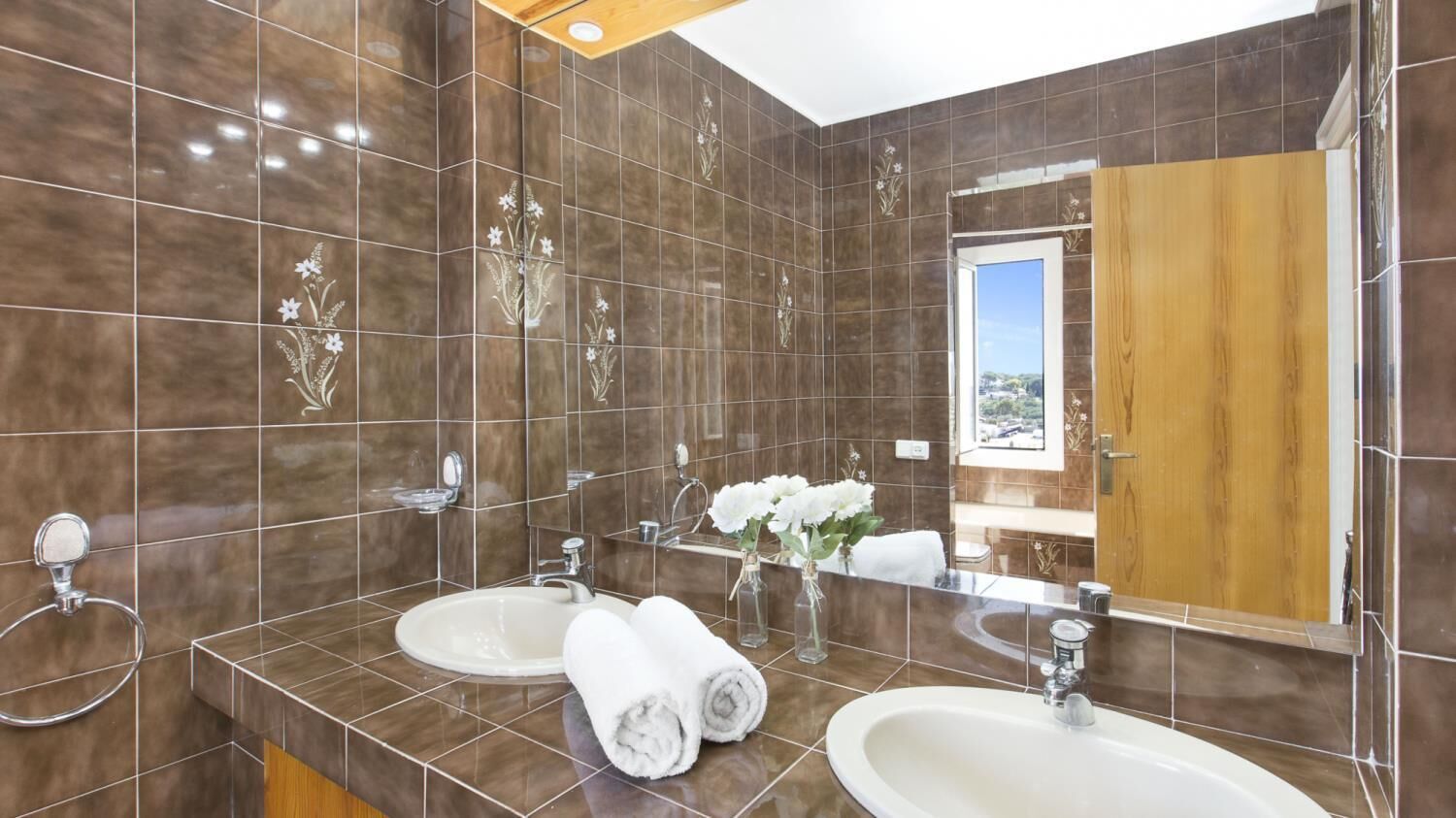 A bathroom with two sinks, a mirror, and a view of the outdoors.