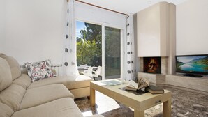 A modern living room with a sofa, a coffee table with books, a fireplace, and a TV. - Vila Lina in Lloret de Mar (Lloret de Mar)