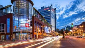 Une rue moderne en milieu urbain, avec un bâtiment aux façades courbes en verre, une enseigne Rogers et un immeuble de la société Canada Life.