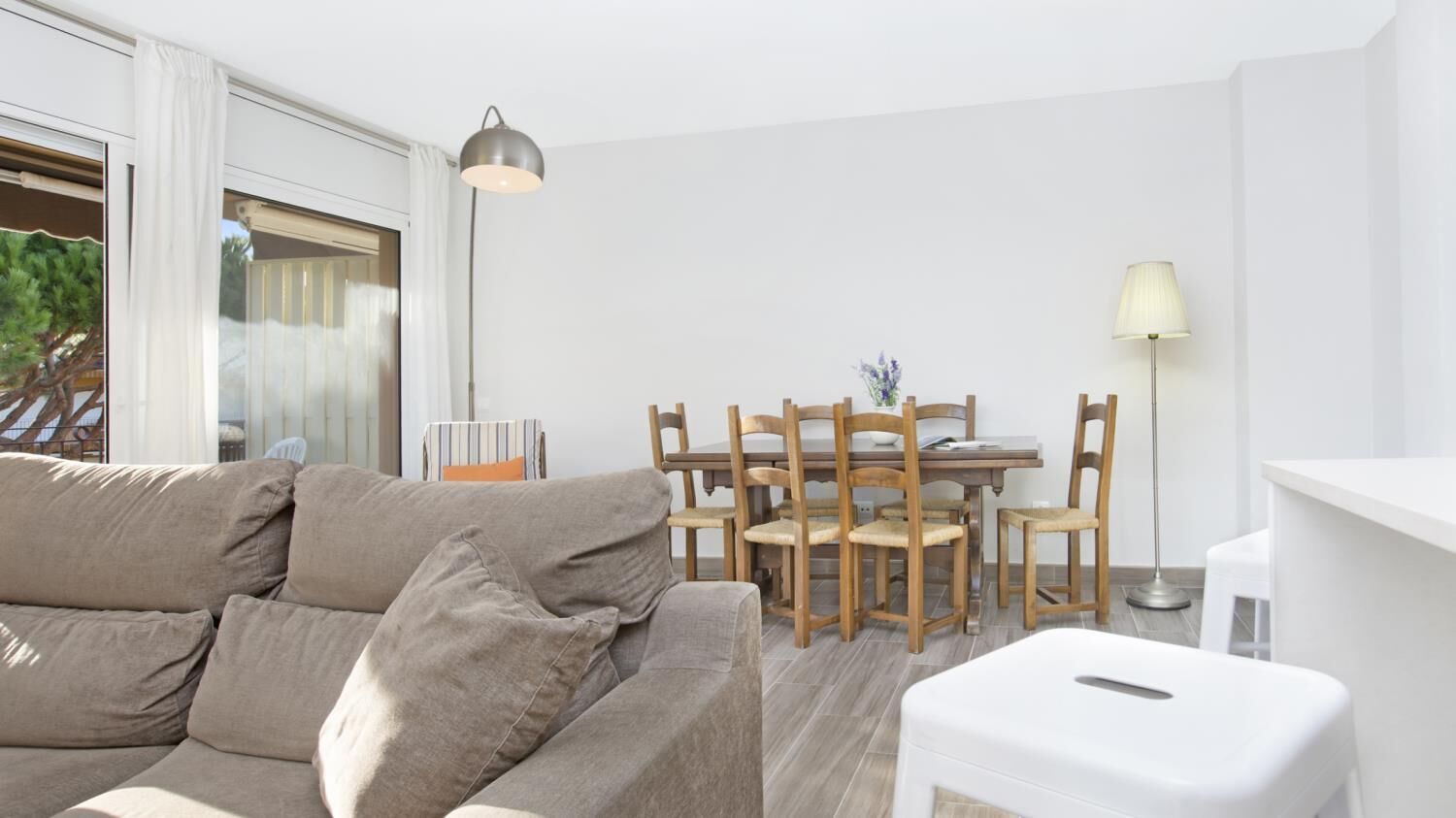 Una sala de estar moderna con un sofá color beige, una mesa de comedor de madera y sillas.