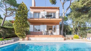 A two-story building with a balcony, a swimming pool in front, and surrounding greenery. - Can Benet 1 in Calella de Palafrugell (Palafrugell)