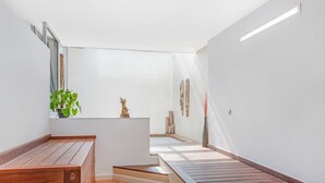 Une salle de bain moderne et minimaliste, avec un banc en bois, une petite plante et une sculpture décorative.