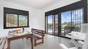 A modern room with a wooden bench, a dining table, and a view of a pool and mountains. - Camelia in Llafranc With 4 Bedrooms and 3 Bathrooms (Vidreres)