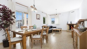A spacious living area with a wooden dining table, chairs, a sofa, and a fireplace. - Carolina in Vidreres (Vidreres)
