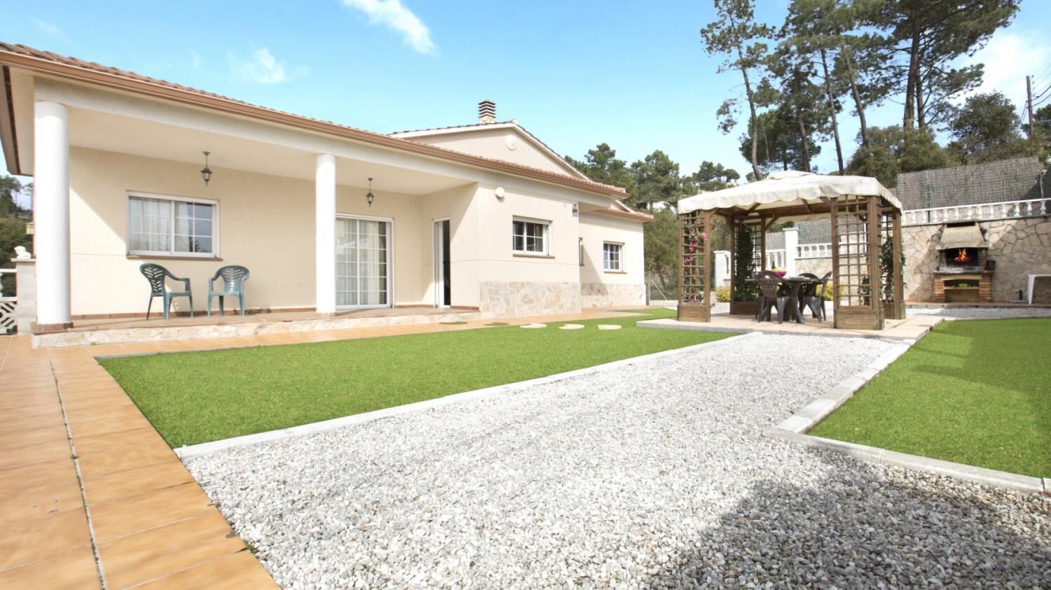 A house with a patio, a barbecue area, and a small garden.