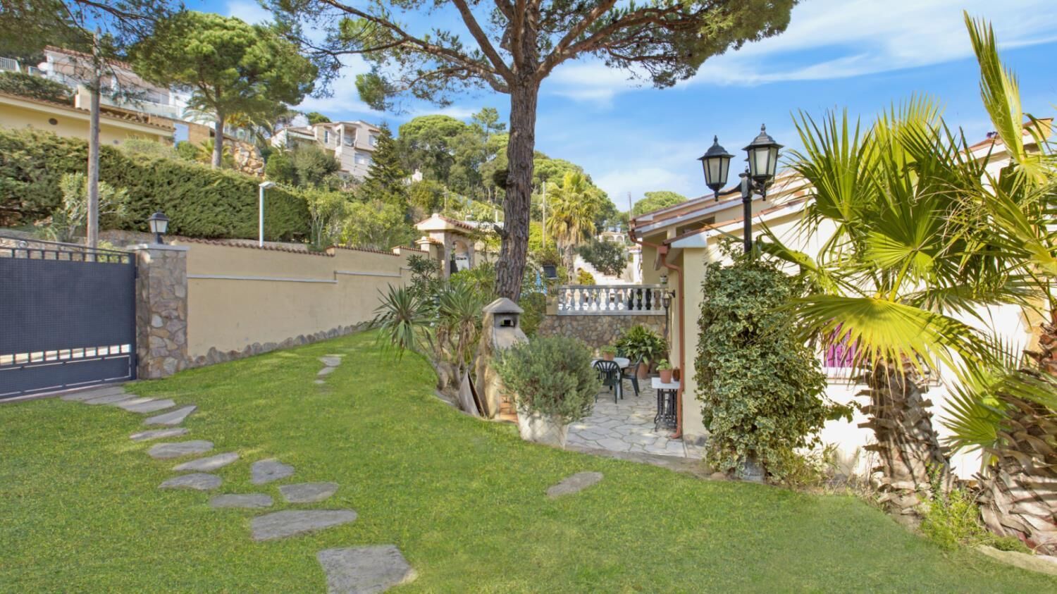 A well-maintained garden with a stone pathway leading to a patio area with outdoor seating.