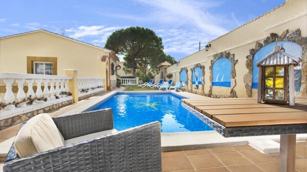 A swimming pool with lounge chairs, a pergola, and a stone wall with arched windows. - Crisantemo in Lloret de Mar (Lloret de Mar)