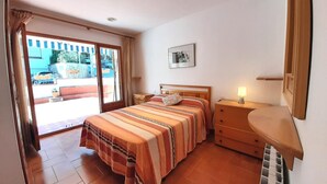 Une chambre à coucher avec un lit, une table de chevet, une commode, une fenêtre avec des rideaux et un tableau au mur.
