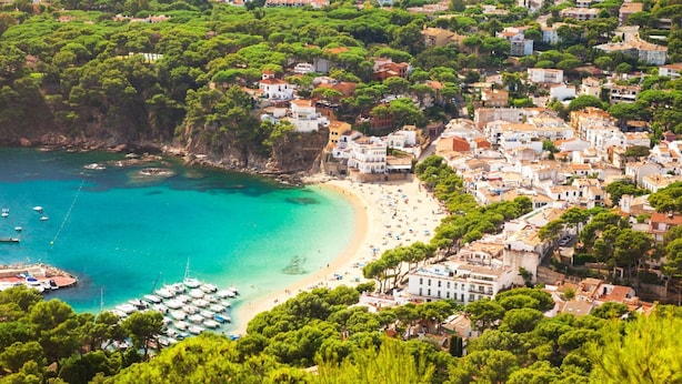 Une ville côtière dotée d’une plage, de bateaux et d’immeubles très rapprochés les uns des autres.