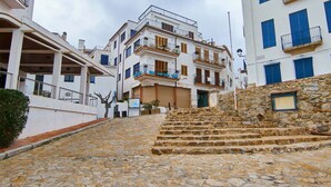 Un escalier en pierre mène à un immeuble doté de nombreux balcons et d’une façade blanche.