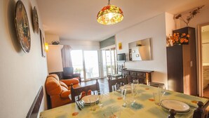A dining area with a table set for four, a sofa, and a kitchen in the background. - Medas 12 in Palau-sator (Pals)