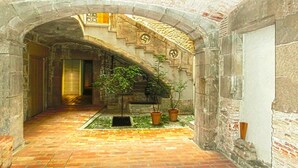 An arched stone corridor with a staircase, potted plants, and a brick floor. - Medas 12 in Palau-sator (Pals)