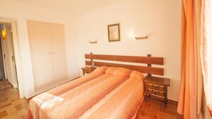 A bedroom with a bed, a nightstand, a wardrobe, and a door. - Medas 12 in Palau-sator (Pals)