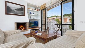 Un salon avec une cheminée, un téléviseur et un balcon offrant une vue sur la ville.