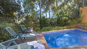 A wooden deck with lounge chairs and a swimming pool surrounded by lush greenery. - Ronda in Llafranc With 4 Bedrooms and 3 Bathrooms (Palafrugell)