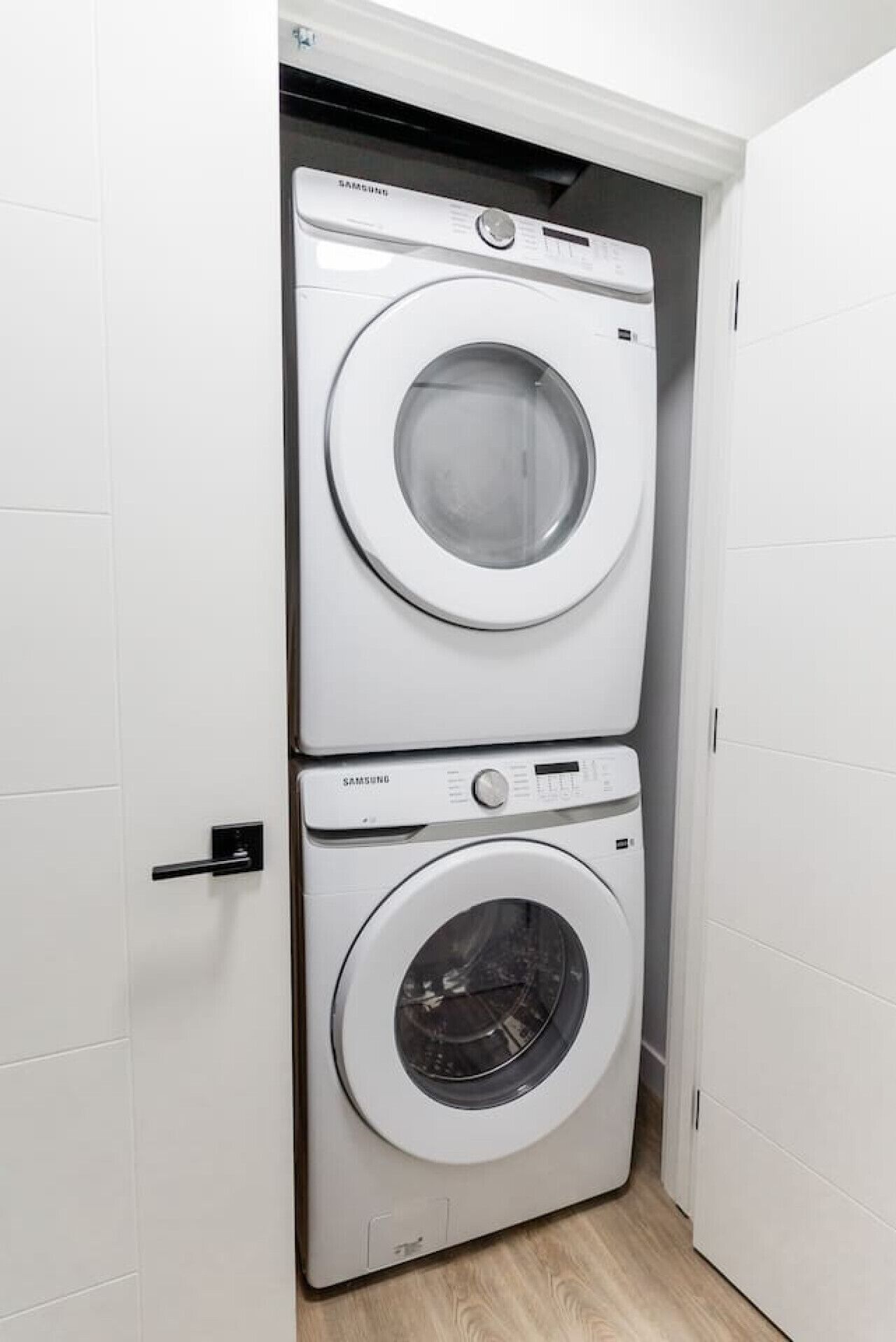Una bugaderia petita i blanca amb dues rentadores superposades.