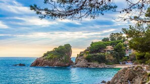 A coastal landscape with rocky outcrops, a beach, and buildings with balconies overlooking the sea. - Mas Pinell 44 in Vidreres (Torroella de Montgrí)