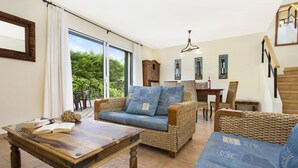 Una sala de estar acogedora con muebles de mimbre, una mesa de centro de madera y un comedor con una mesa y sillas.