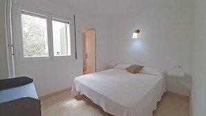Un dormitorio con cama, escritorio y ventana.