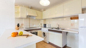 A compact kitchen with white cabinets, a washing machine, a microwave, and a sink. - Illa 23 in Calella de Palafrugell (Palafrugell)
