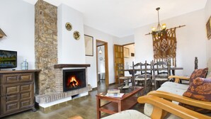A cozy living room with a stone fireplace, wooden furniture, and a chandelier. - Bravo in Llafranc With 3 Bedrooms and 1 Bathrooms (Palafrugell)