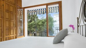 A bedroom with a large window, wooden wardrobe, and a bed with a pillow and orchid. - Bravo in Llafranc With 3 Bedrooms and 1 Bathrooms (Palafrugell)