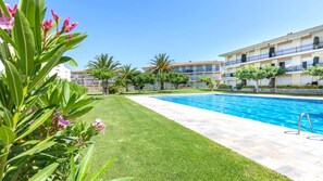 A swimming pool with a clear blue water, surrounded by a well-maintained lawn and various plants. - Costa Brava E-6 in Lloret de Mar (Palafrugell)