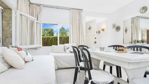 Une pièce comprenant un lit, une table à manger avec des chaises, une fenêtre avec des rideaux et un miroir au mur.