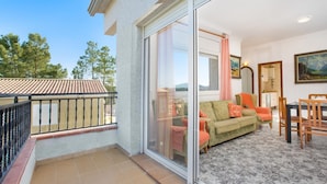 A balcony with a tiled floor and a glass door leading to a living area with a sofa, chairs, and a dining table. - Alonso in Vidreres With 4 Bedrooms and 1 Bathrooms (Vidreres)