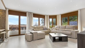 A spacious living room with a sectional sofa, a coffee table, and large windows offering a view of the city. - Paulina in Lloret de Mar (Lloret de Mar)