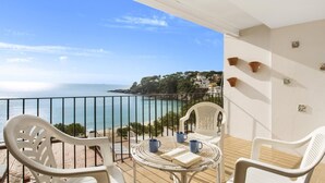 A balcony with white plastic chairs, a wicker table, and two blue mugs. - Pruneda in Llafranc With 2 Bedrooms and 1 Bathrooms (Palafrugell)