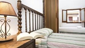 A bedroom with a wooden headboard, a bedside lamp, a striped bedspread, and a mirror on the wall. - Pruneda in Llafranc With 2 Bedrooms and 1 Bathrooms (Palafrugell)