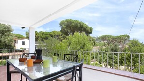 A balcony with a glass table, chairs, and a coffee maker. - Pandora 1 in Llafranc (Palafrugell)