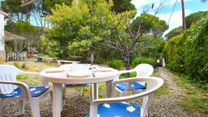 An outdoor patio with a round table and white plastic chairs, surrounded by greenery and trees. - Sirena in Llafranc With 1 Bedrooms and 1 Bathrooms (Palafrugell)