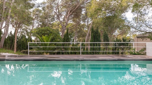 A swimming pool with a metal railing, surrounded by trees and greenery. - Ferran in Llafranc With 4 Bedrooms and 2 Bathrooms (Palafrugell)
