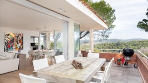 A modern outdoor dining area with a wooden table and white chairs, overlooking a scenic landscape. - Ferran in Llafranc With 4 Bedrooms and 2 Bathrooms (Palafrugell)