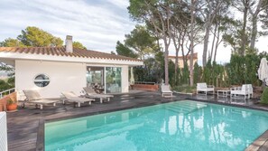 Ein moderner Poolbereich mit klarem Pool, Liegestühlen und einem Gebäude mit großen Fenstern.