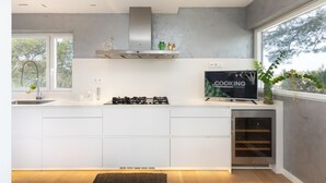 A modern kitchen with white cabinetry, a built-in gas stove, a stainless steel range hood, and a wine cooler. - Ferran in Llafranc With 4 Bedrooms and 2 Bathrooms (Palafrugell)