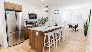 A modern kitchen with a central island, stainless steel appliances, and pendant lighting. - Perfect Comfy Retreat | Premium Location Home Stay (Winnipeg)