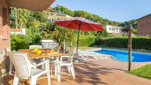 A patio with a table and chairs, a red umbrella, and a swimming pool. - Llevant 2 in Lloret de Mar (Lloret de Mar)