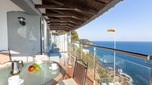 A balcony with a glass table, chairs, and a view of the ocean. - Canyelles in Lloret de Mar (Lloret de Mar)