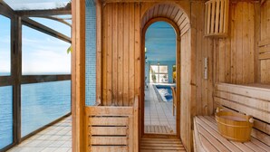 Una sauna de madera con vista a una piscina y al mar.