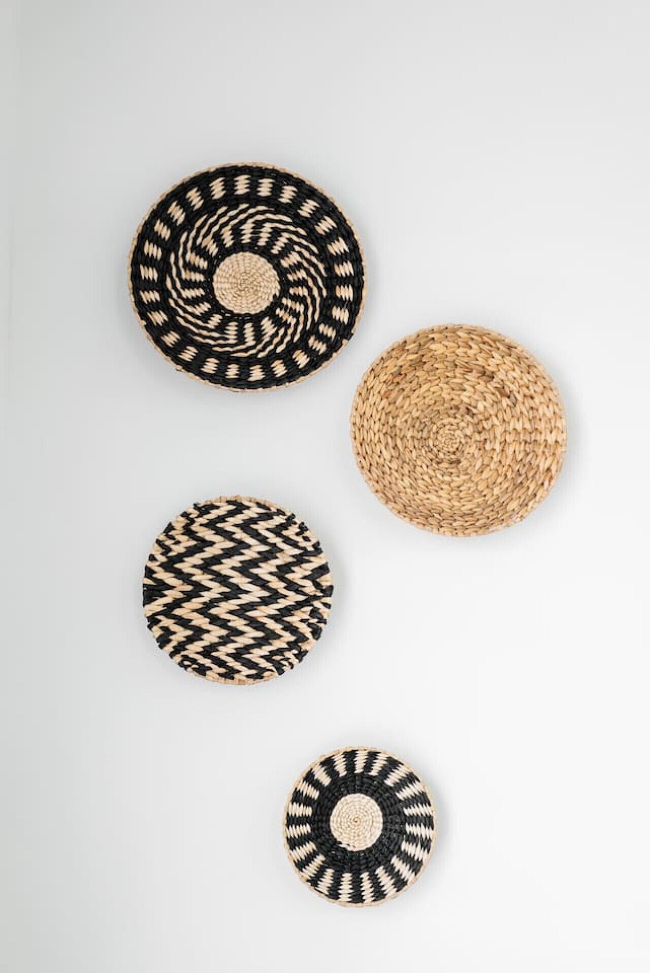 Quatre objets circulaires tissés, chacun présentant un motif différent.
