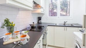 Eine moderne Küche mit weißen Schränken, einer schwarzen Arbeitsplatte, einer Kaffeemaschine und einem Fenster mit Blick auf Grünflächen.
