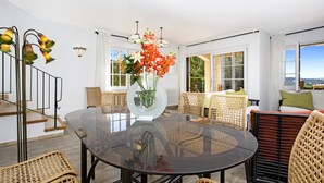A modern living room with a glass-top table, wicker furniture, and a view of the outdoors. - Ses Brises 31 in Llafranc (Palafrugell)