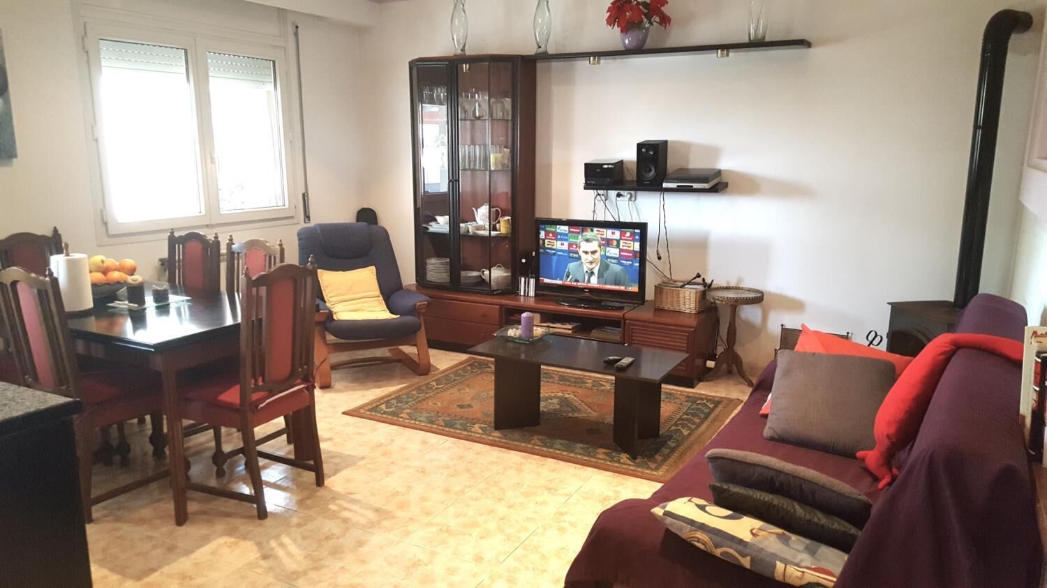 A living room with a TV, a dining table, chairs, a sofa, and a cabinet.
