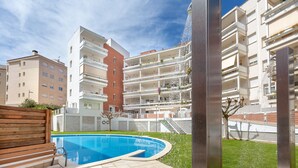 Un moderno edificio de apartamentos con piscina, balcones y un césped bien cuidado.
