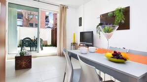 Una sala de estar moderna con comedor, televisor y balcón con vista a edificios.