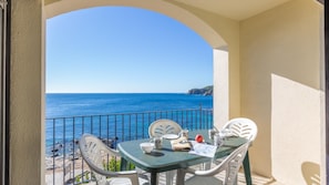 Uma varanda com mesa e cadeiras, com vista para a costa.