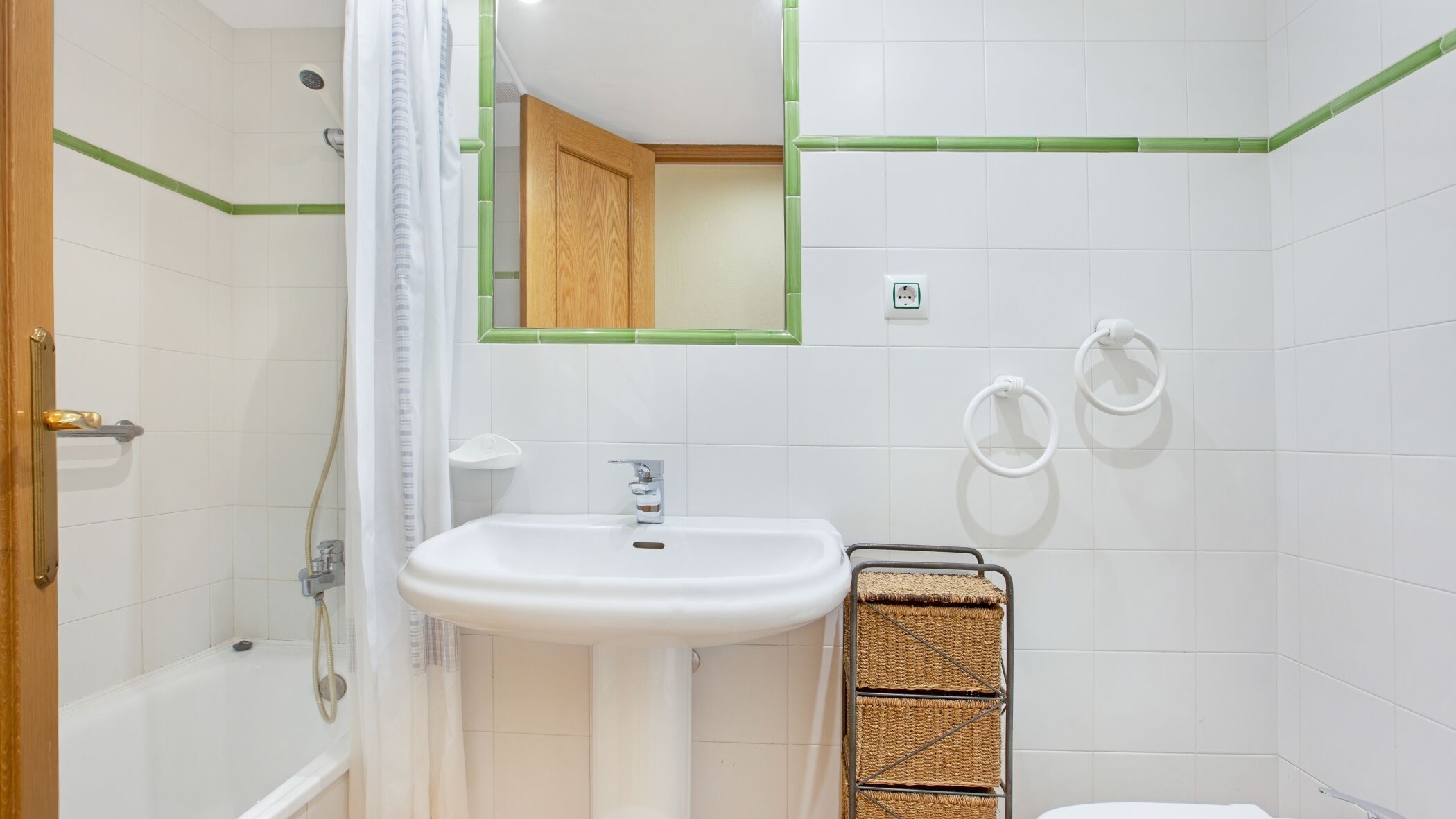 Egy fürdőszoba, amelyben fehér mosdókagyló, zuhanyzó és WC található.